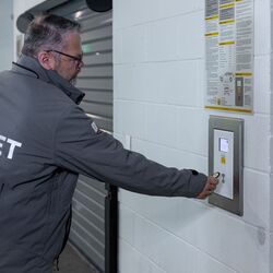 L’image montre une personne devant le panneau de commande d’un système de stationnement automatisé, confirmant le processus de stockage et lançant ainsi le transport automatique du véhicule vers une place de stationnement disponible.