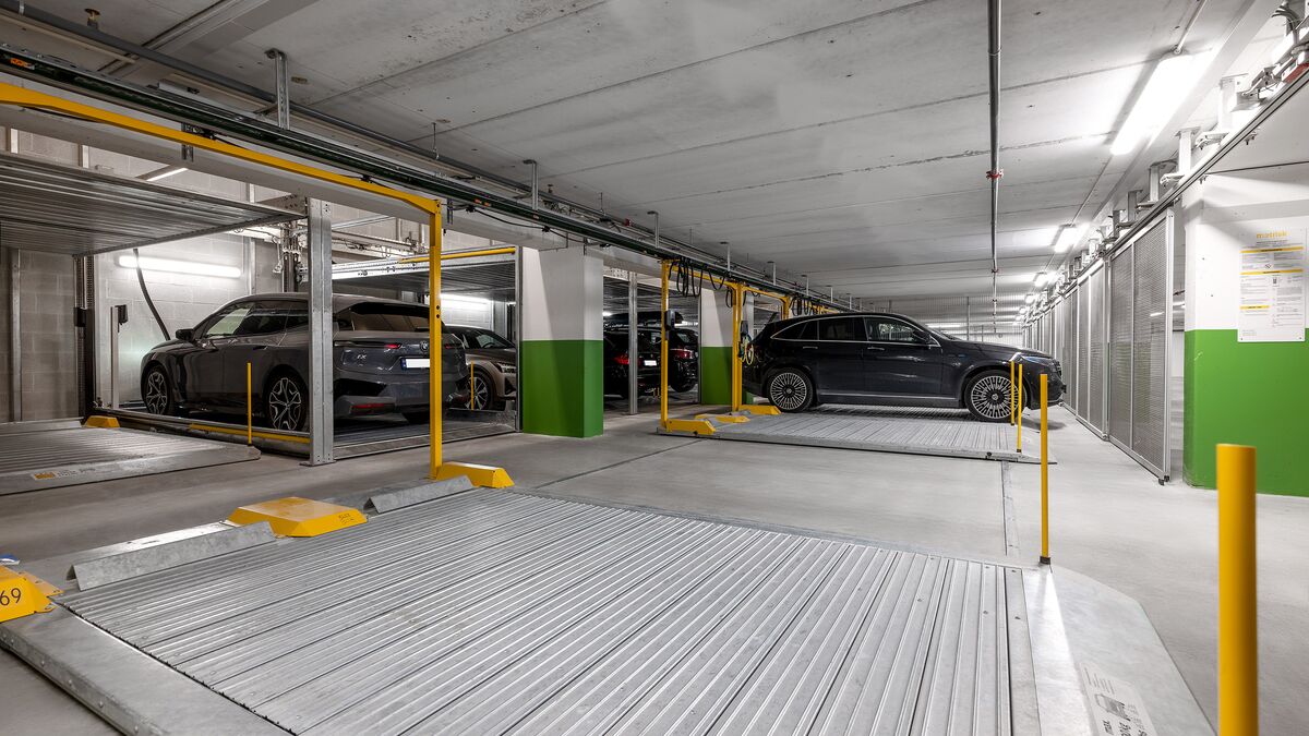 Varios coches están estacionados sobre la plataforma de aparcamiento en un garaje subterráneo.