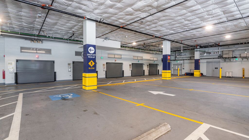 L’image montre l’entrée d’un système de stationnement automatisé dans un parking souterrain moderne avec plusieurs portes d’accès.