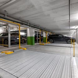 Varios coches están estacionados sobre la plataforma de aparcamiento en un garaje subterráneo.