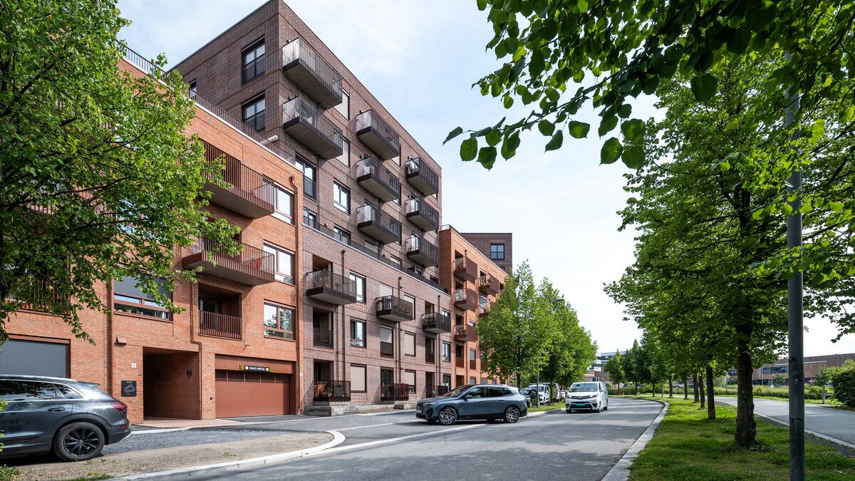 Complejo residencial moderno donde un vehículo entra en un garaje equipado con un sistema de aparcamiento integrado.