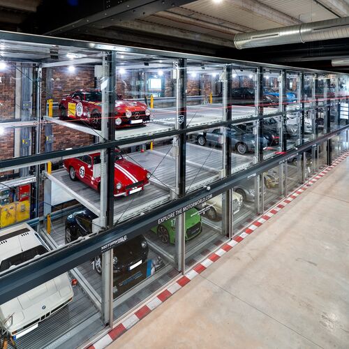 An oblique view of the car park at Motorworld in Mallorca, featuring sports cars in glass display cases