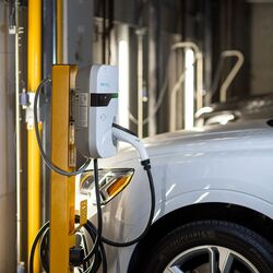 Un véhicule est stationné sur la plateforme d’un système de stationnement et est rechargé grâce à l’installation de recharge intégrée pour véhicules électriques.