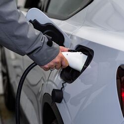 L’image montre le processus de recharge d’un véhicule électrique, au cours duquel un connecteur de recharge est branché au véhicule afin de recharger la batterie pendant le processus de stationnement.