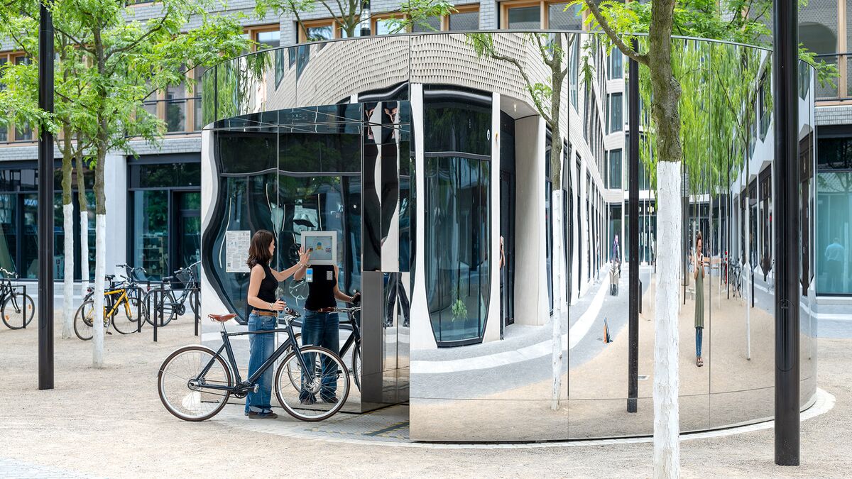 Una mujer con bicicleta maneja un monitor en el sistema de aparcamiento para bicicletas