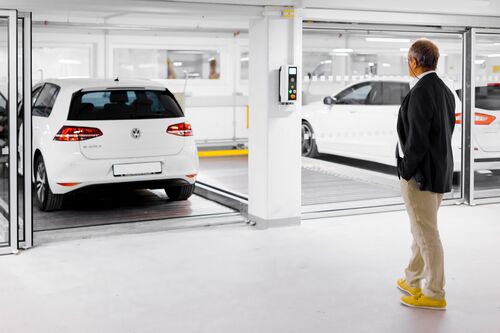 Mann steht vor einem Parksystem mit Autos