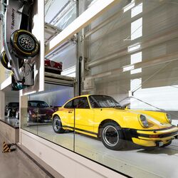 Un coche clásico amarillo aparcado en un sistema de aparcamiento en un museo