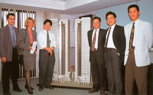 Six people standing in front of a model of a high-rise building