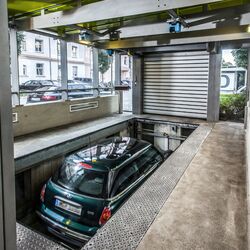 Auto steht in einer Einfahrtskabine auf einer Parkplatte und fährt nach unten