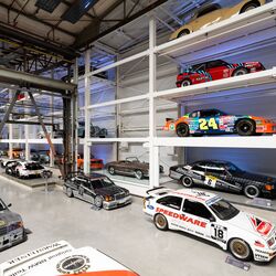 A wall-mounted shelf full of cars in a museum