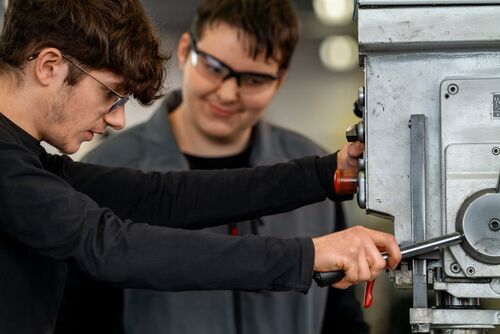 Zwei Männer, die an einer Maschine arbeiten