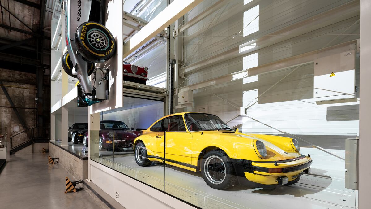 Un coche clásico amarillo aparcado en un sistema de aparcamiento en un museo