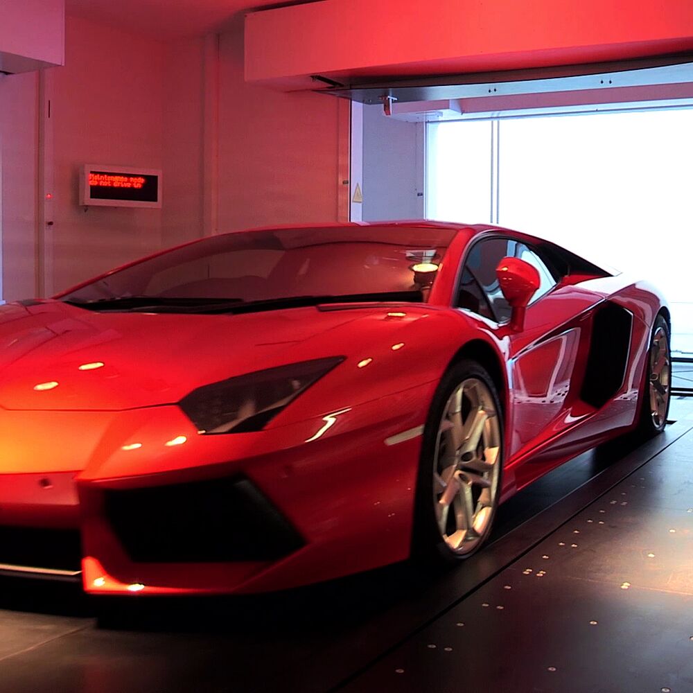 A red car is parked in the entry bay of a parking system