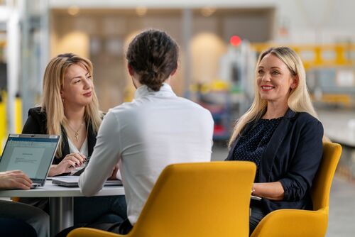 Mehrere Personen mit Laptops sitzen an einem Tisch