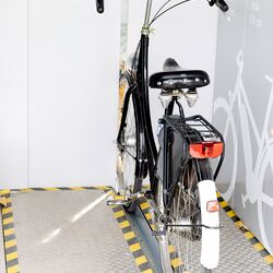 Fahrrad auf einer Radschiene vor einem automatischen Fahrradparksystem