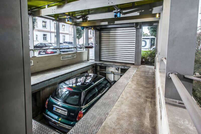 Auto steht in einer Einfahrtskabine auf einer Parkplatte und fährt nach unten