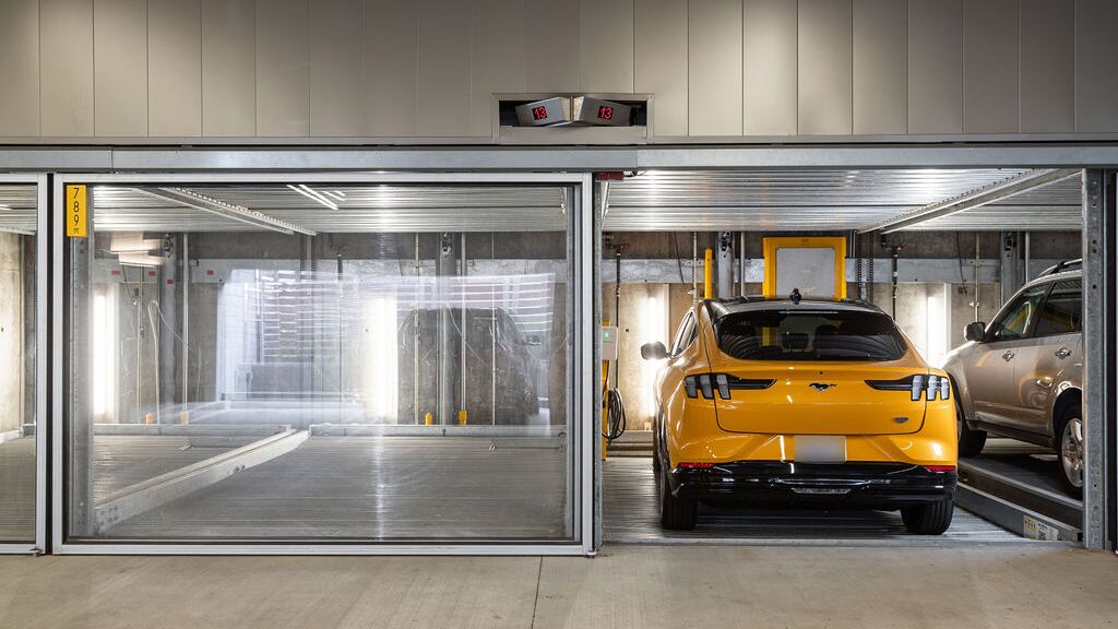 L’image montre plusieurs véhicules dans des emplacements vitrés d’un système de stationnement dans un parking souterrain moderne.