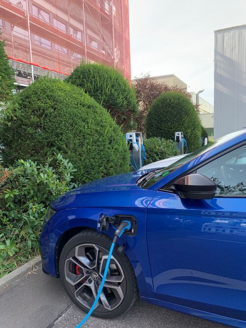 Blaues Auto wird an einer E-Ladestation aufgetankt