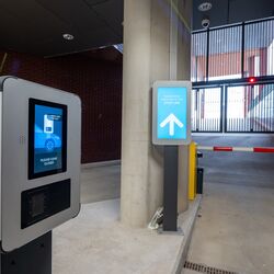 Ausfahrt aus einem modernen Parksystem mit Zutrittsterminal, digitaler Fahrerinformation und automatischer Schrankenanlage für die kontrollierte Fahrzeugausfahrt.